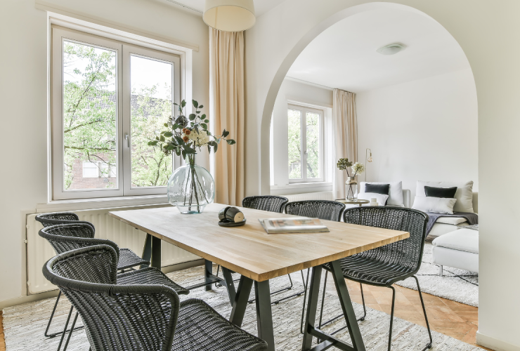 A dining room table with chairs and a vase of flowers.