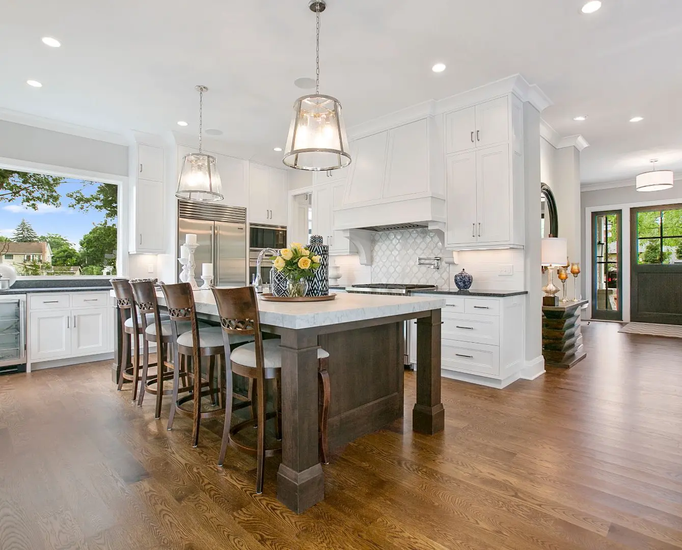 A kitchen with white cabinets and wooden floors